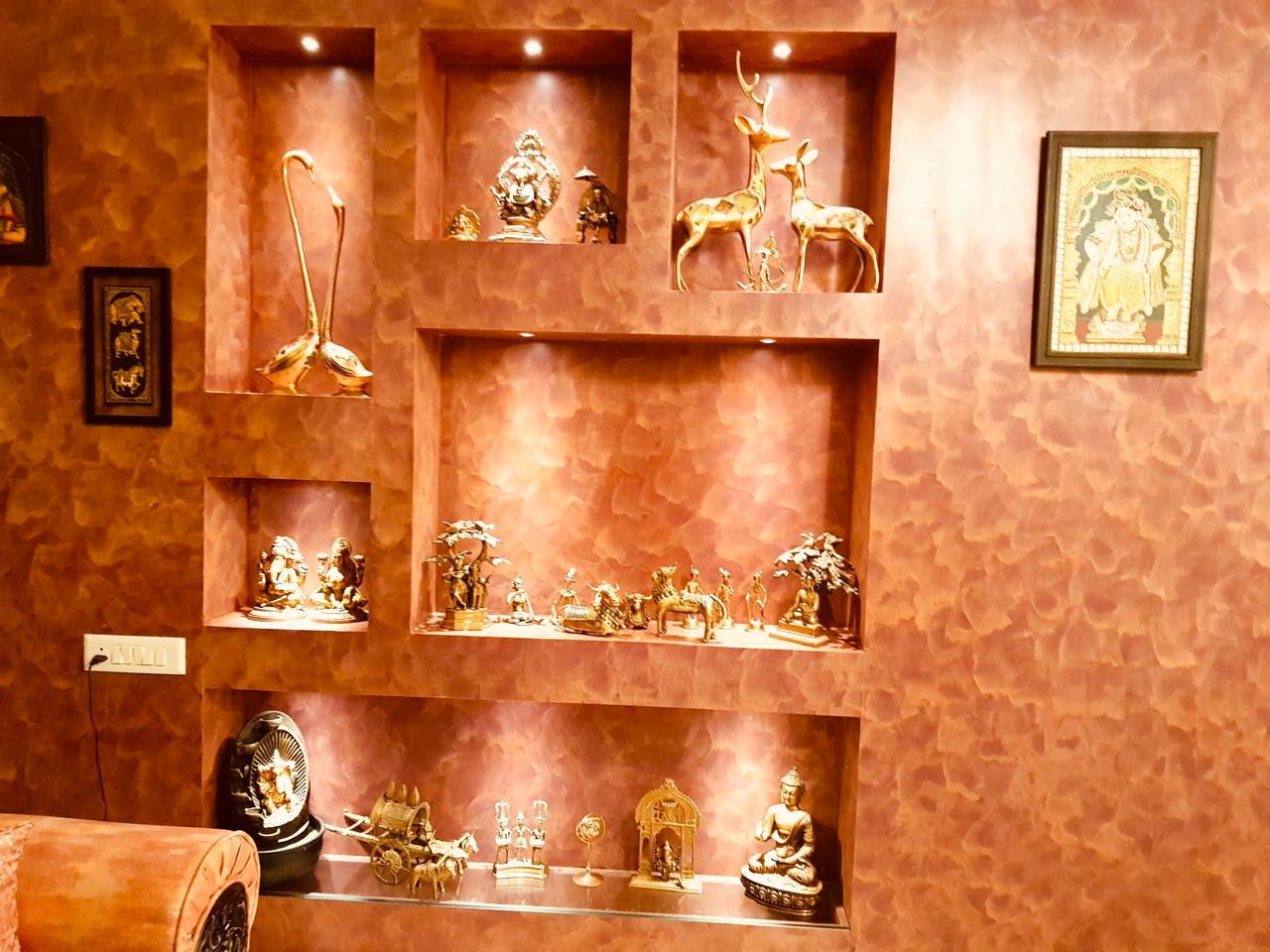 Textured feature wall with built-in display niches and curated brass decor pieces by Assankhhya